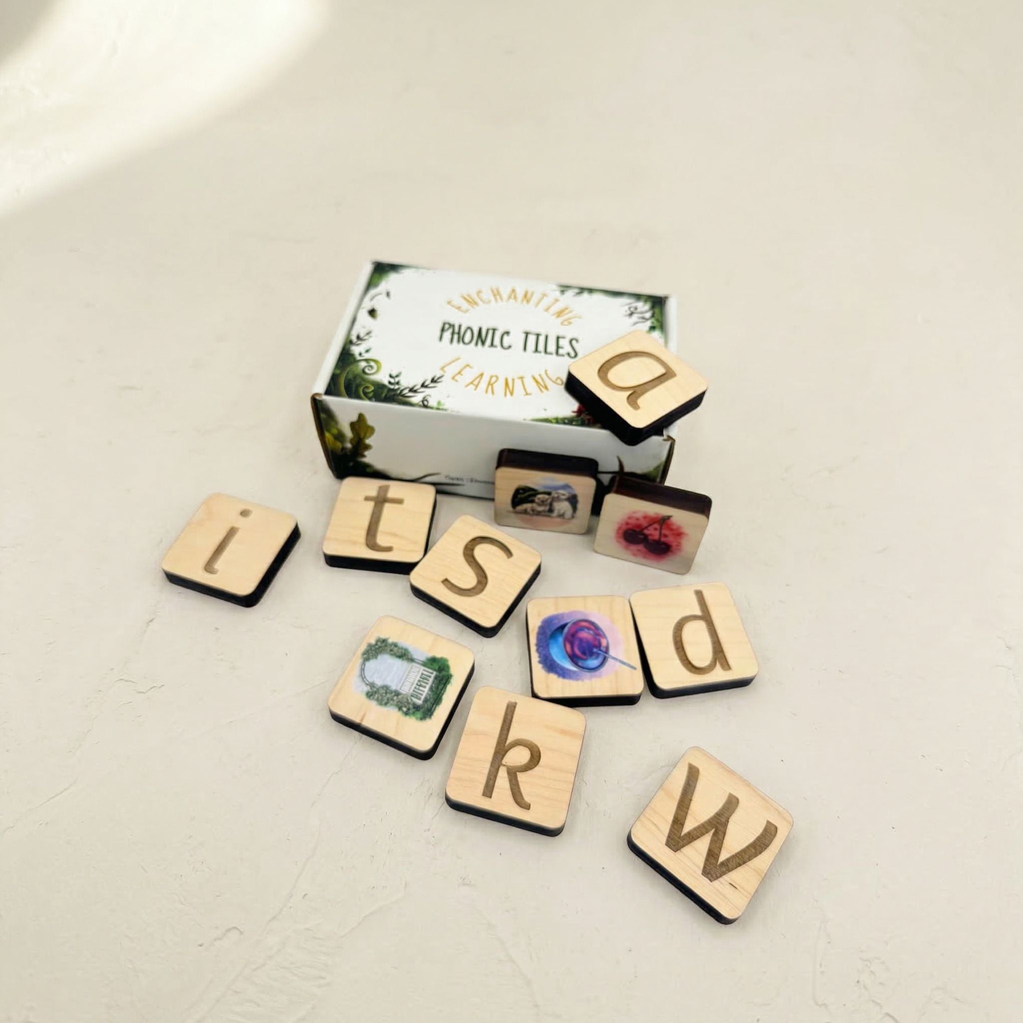 Wooden phonic tiles with letters and a box labeled 'Phonic Tiles' on a light surface.