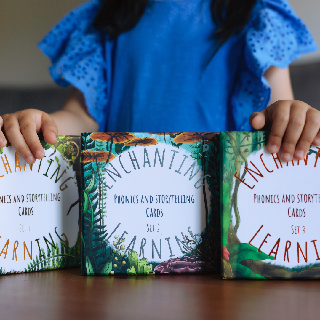 a girl holding three sets of phonics cards.