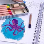 Watercolour pencils and octopus card with open Storywriter's book.